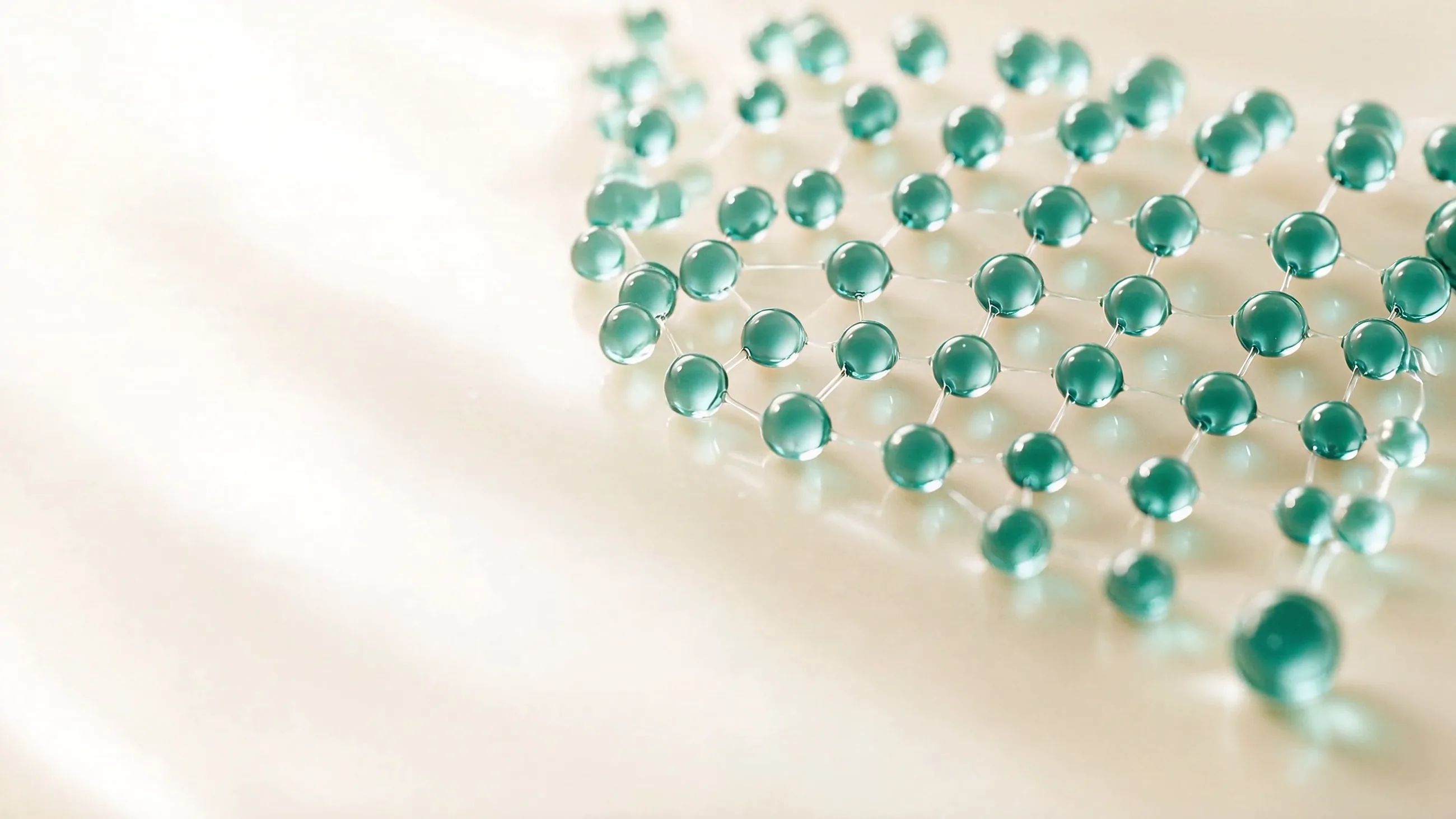 Retícula ordenada de gotas de gel verde azulado sobre una superficie color crema